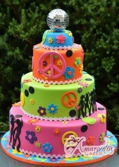 a multi - tiered cake decorated with flowers, peace signs and other colorful decorations