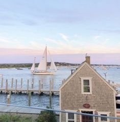 a sailboat is in the water next to a small house and dock with boats