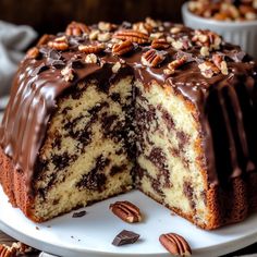 a cake with chocolate frosting and pecans is cut in half on a white plate