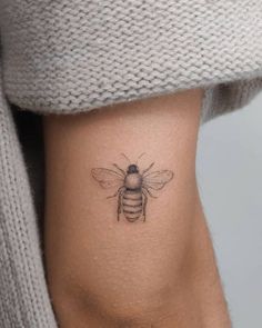 a woman's stomach with a small bee tattoo on her left side ribcage