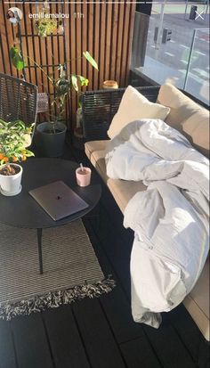 a laptop computer sitting on top of a wooden table next to a plant filled with potted plants