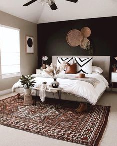 a bedroom with a bed, rug and ceiling fan in the corner is decorated with black and white accents