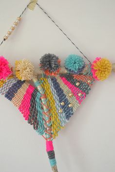 a multicolored piece of art hanging on the wall with beads and tassels