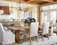 the dining room table is surrounded by white chairs and beige upholstered chairs with blue flowers on them