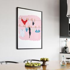 a kitchen with an art piece hanging on the wall and fruit in front of it