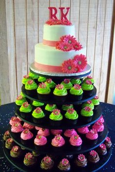 a three tiered cake with pink and green cupcakes