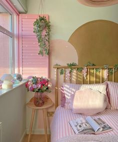 a bed with pink and white sheets in a bedroom next to a window covered in greenery