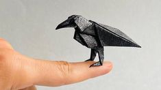 a hand holding a black origami bird