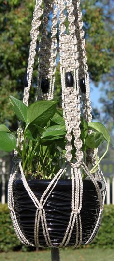 a potted plant hanging from a metal pole with beads and chains attached to it