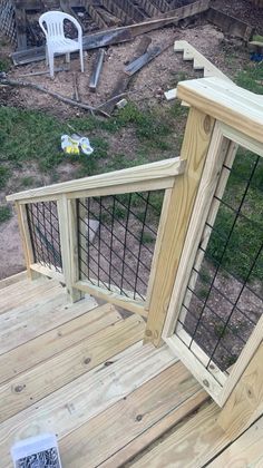 a wooden deck with a wire fence around it and a white chair in the background