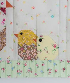 two birds are sitting next to each other on a patchwork quilted wall hanging