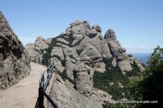 a path leading to the top of a mountain with rocks on both sides and trees in the foreground