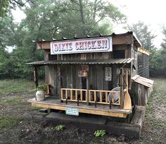 an old wooden shack sitting in the middle of a field with a sign on it