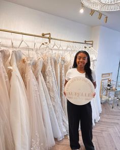 a woman holding a sign in front of wedding gowns