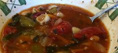 a white bowl filled with vegetable soup on top of a table