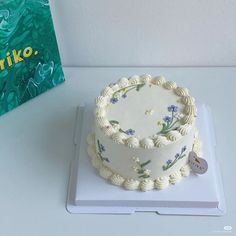 a white cake sitting on top of a table next to a book