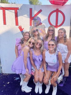 a group of women posing for a photo in front of a sign