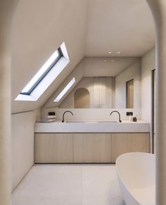 an attic bathroom with skylights and white counter tops, along with a bathtub in the foreground