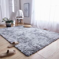 a living room with a rug and shoes on the floor, next to a window