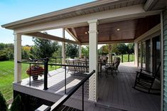 a covered deck with chairs and tables on it in the middle of a grassy area