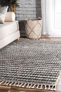 a black and white rug with tassels on the floor next to a couch