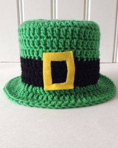 a green crocheted hat with a yellow square on the front and black band