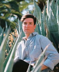 a man sitting in the middle of some plants