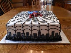 a spiderman cake sitting on top of a wooden table next to a dining room table