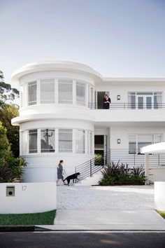 a woman walking her dog in front of a large white house with balconies