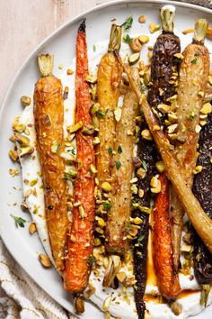 a white plate topped with carrots and other food on top of a wooden table