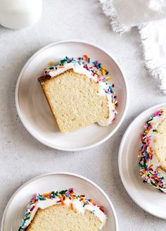 three slices of cake with sprinkles on white plates next to a glass of milk