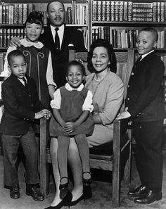 a black and white photo of a family in front of bookshelves