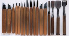 an assortment of wooden utensils are arranged on a white surface