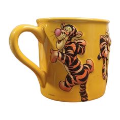 a yellow coffee mug with a cartoon tiger on it's front and side handles