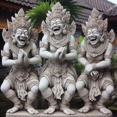 three white statues with laughing faces in front of a building