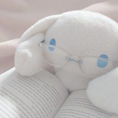 a white stuffed animal wearing glasses reading a book