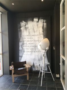 a room with a chair, lamp and large chalkboard on the wall