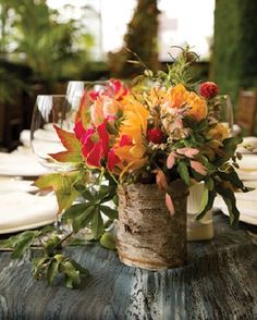 a vase filled with flowers sitting on top of a wooden table covered in white plates