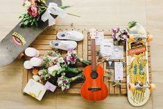 a skateboard, guitar, and flowers on a wooden pallet next to each other