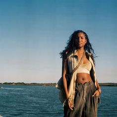 a woman standing on the edge of a boat with her hands in her pockets and looking off into the distance