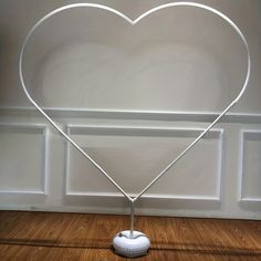 a white heart shaped lamp on top of a wooden floor in front of a wall