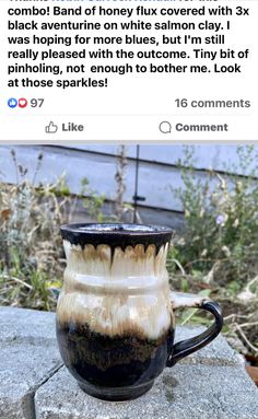 a black and white coffee cup sitting on top of a rock