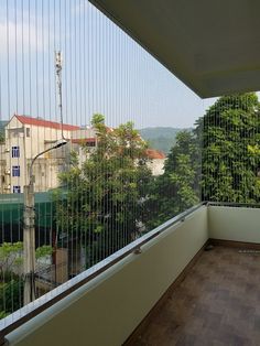 an empty balcony with trees and buildings in the backgroung, as seen from outside