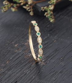 an image of a gold ring with green and white stones on the inside of it