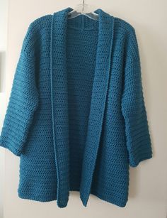 a blue knitted cardigan hanging on a wall