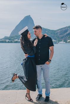 a man and woman standing next to each other near the water