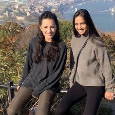 two young women sitting on top of a hill