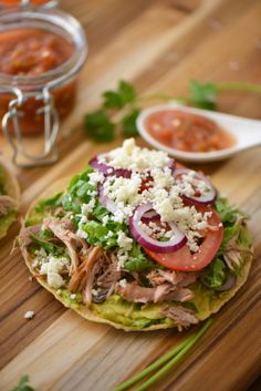 two tortillas topped with meat, cheese and veggies on a cutting board