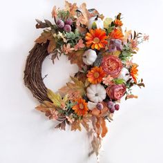 a wreath with flowers and leaves hanging on the wall