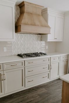 a stove top oven sitting inside of a kitchen next to white cupboards and drawers